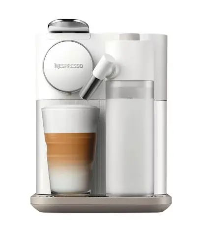 Weisse Kaffeemaschine mit Glas und Kaffee mit Milchschaum